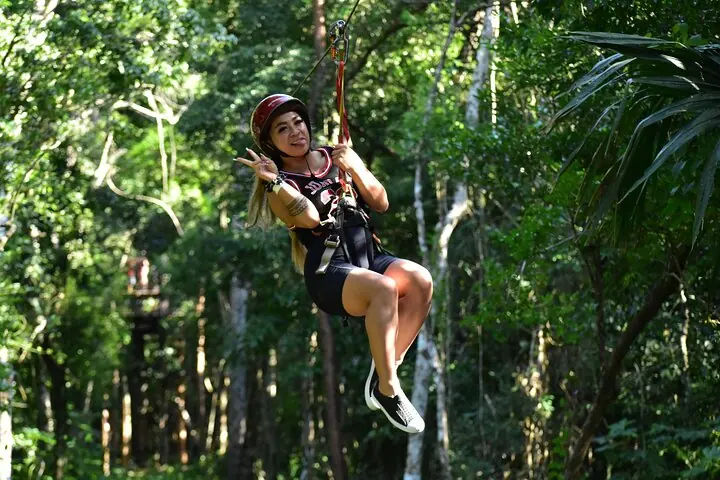 Helmeted guest with guide support on the Kin-Ha zipline route